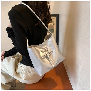 Silver shoulder bag detail showing metallic texture and unique 3D knot design feature