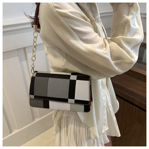 Close-up of tricolor plaid square crossbody bag with gold chain strap on shoulder