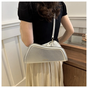 Close-up of silver asymmetric shoulder bag with shiny metallic finish and gold text logo