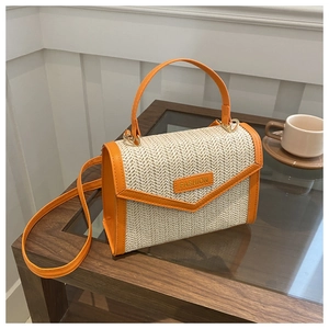 Détail du sac bandoulière en paille avec finitions en cuir orange et étiquette mode