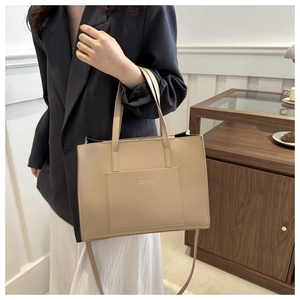 Detail of light beige tote bag featuring gold lettering and adjustable shoulder strap