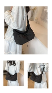 Three-angle view of a large black nylon crossbody bag featuring pleated drawstring detail