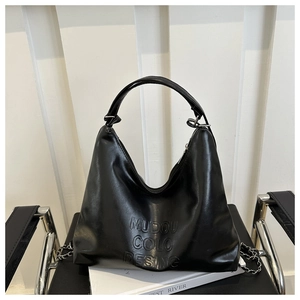 Detail of black glossy leather bag with embossed lettering and silver metal chain