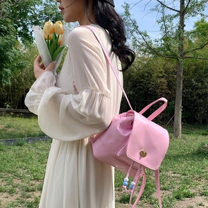 Pink mini PU leather backpack with drawstring closure and beaded strap in outdoor setting