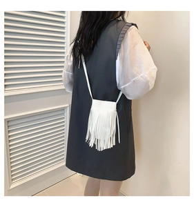 White fringe crossbody bag with long tassels shown from a back view on a model