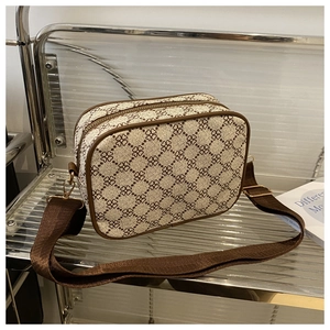 Gros plan du sac beige à imprimé trèfles avec une bandoulière large en nylon réglable