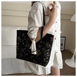Detailed close-up of butterfly embroidery and metal studs on a black canvas tote bag
