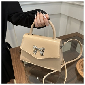 Detail of beige bow-knot handbag with silver mirror ornament and top handle