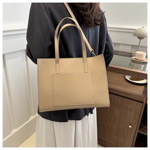 Detail view of large beige PU leather tote bag with gold logo and adjustable shoulder strap