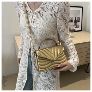 Detail of gold chevron quilted shoulder bag with chain strap and metallic finish