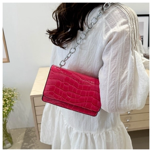 Detail of pink crocodile embossed handbag with a chunky silver chain strap for women