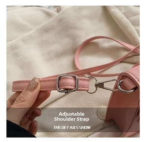 Close-up of pink cross-grain leather bag with silver metal buckle and adjustable strap