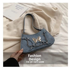 Detalle del bolso de hombro en denim con mariposa plateada y adornos de cadena