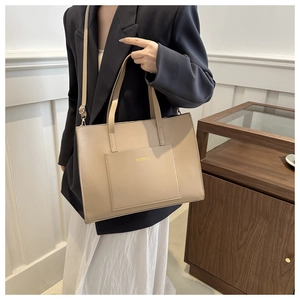Detail of beige tote bag showing texture, dual handles, and adjustable shoulder strap