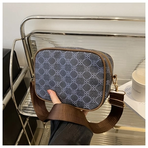 Détail du sac bandoulière floral bleu avec bordure en cuir marron et large sangle