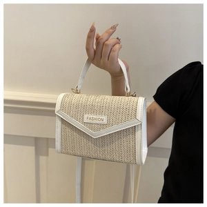 Détail du sac à bandoulière en paille avec bordure en cuir blanc et plaque en métal