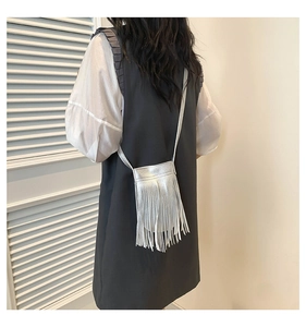 Detail shot of silver mini crossbody bag with long tassels on a model shoulder