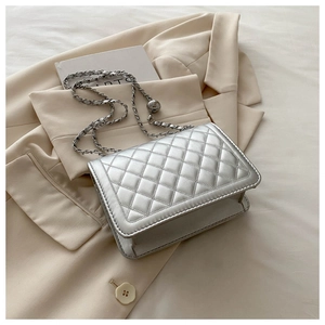 Close-up of silver quilted crossbody bag with chain strap and metal ball charm