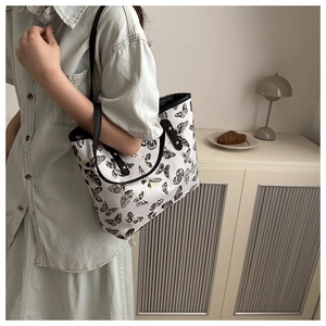 Close-up of artistic black butterfly prints on white tote bag with metal rivet details