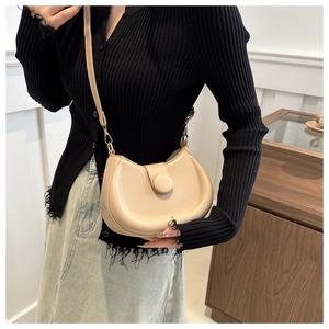 Close-up of minimalist beige semi-circular shoulder bag with stylish round decorative buckle