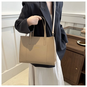Detail view of beige tote bag with front pocket and shoulder strap on model