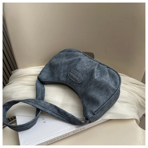 Detail view of a gray washed texture crescent bag resting on a chair with aesthetic props