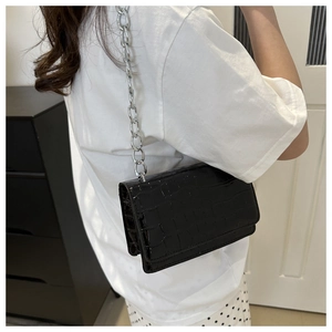 Close-up of a black crocodile pattern crossbody bag with a chunky silver metal chain strap