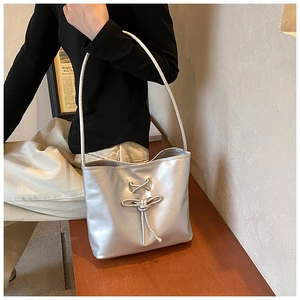 Close-up of silver shoulder bag featuring handcrafted knot and bow metallic leather detail