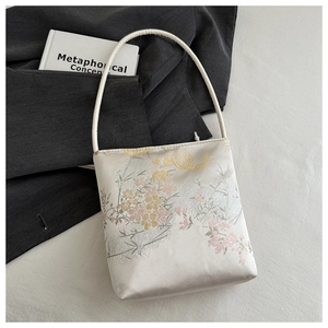 Détail du sac à main en satin blanc avec broderie florale et poignée en soie élégante