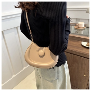 Detail of beige crescent shoulder bag with unique matching covered button and adjustable strap