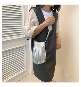 Silver fringe crossbody bag with metallic tassels shown styled on a model's outfit