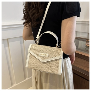 Detail of straw shoulder bag featuring white leather trim and fashion brand plaque