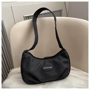 Detail of minimalist black hobo bag on a chair showing the fashion emblem and smooth fabric