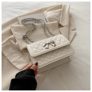 Detail of quilted leather handbag with silver bow buckle and elegant metal chain strap