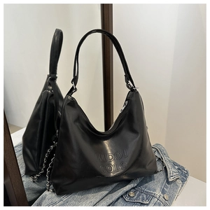 Detail of embossed logo and silver chain on a black oil leather shoulder tote bag