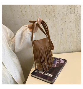 Detail of a brown leather bucket bag with dense fringes and adjustable shoulder strap