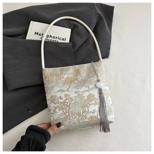 Détail du sac seau en satin jacquard chinois avec pavillon doré et pompon gris élégant
