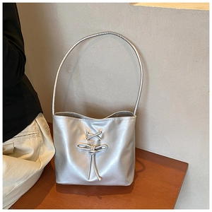 Detailed close-up of metallic silver bucket bag with ribbon bow and slim shoulder strap