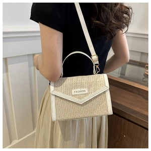 Detail of bohemian woven crossbody bag with white leather trim and gold fashion buckle