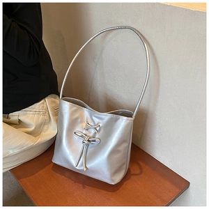 Close-up of silver shoulder bag with metallic finish and chic bow drawstring detail