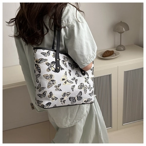Detail of butterfly print tote bag with black straps and elegant gold metal ring buckle
