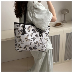 Close-up of canvas tote bag with black butterfly prints and gold rivet details