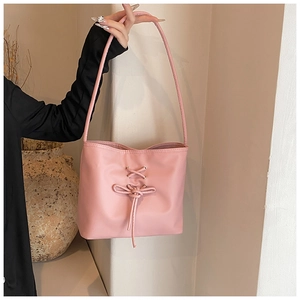 Detailed view of pink shoulder bag featuring a decorative bow and lace-up design detail