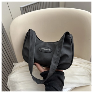 Close-up of black crescent-shaped fabric shoulder bag with FASHION & BAG label