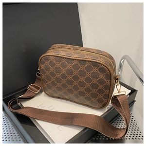 Détail d'un sac caméra marron avec motif floral et large bandoulière en tissu
