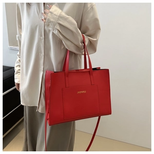 Detailed side view of a large red leather tote bag with elegant gold logo and shoulder strap