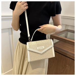 Détail d'un sac en paille tressée avec bordure blanche et plaque dorée Fashion