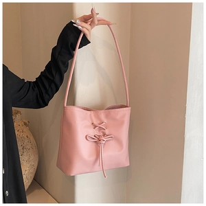 Detailed view of pink leather shoulder bag featuring decorative lace-up bow and thin strap