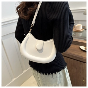 Detailed view of a creamy white puffy crescent bag worn over a black summer outfit