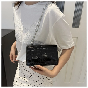 Detail of black crocodile texture small square bag with silver metal chain strap